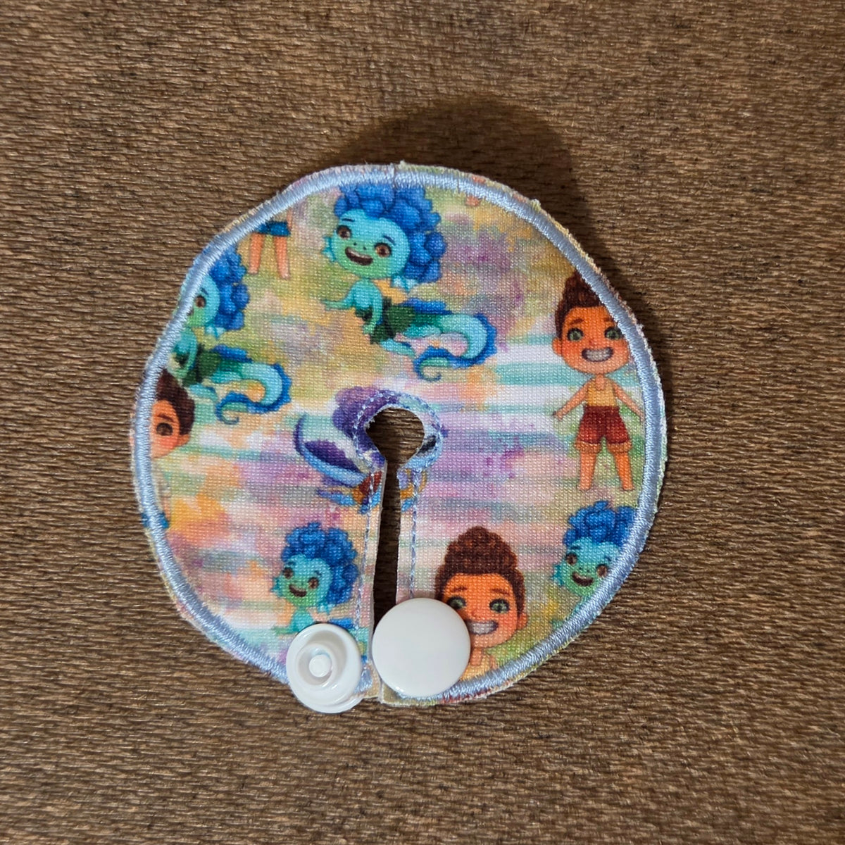 Mini gtube pad in sea monster boy print on striped blue and purple watercolor bled background