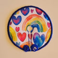Circular patch with rainbow and heart design on a beige background