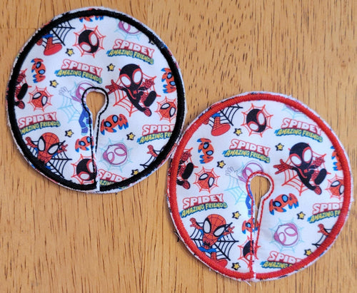 Two round Spider-Man themed coasters on a wooden surface