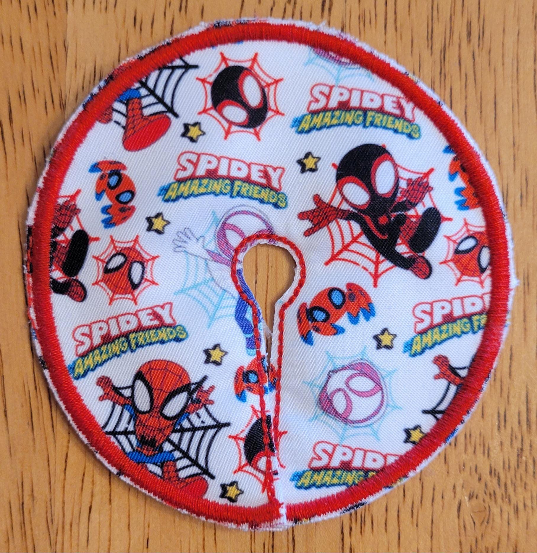 Circular patch with Spider-Man-themed designs on a wooden surface