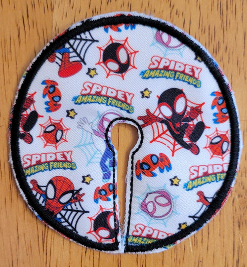 Circular fabric patch with Spider-Man-themed designs on a wooden surface