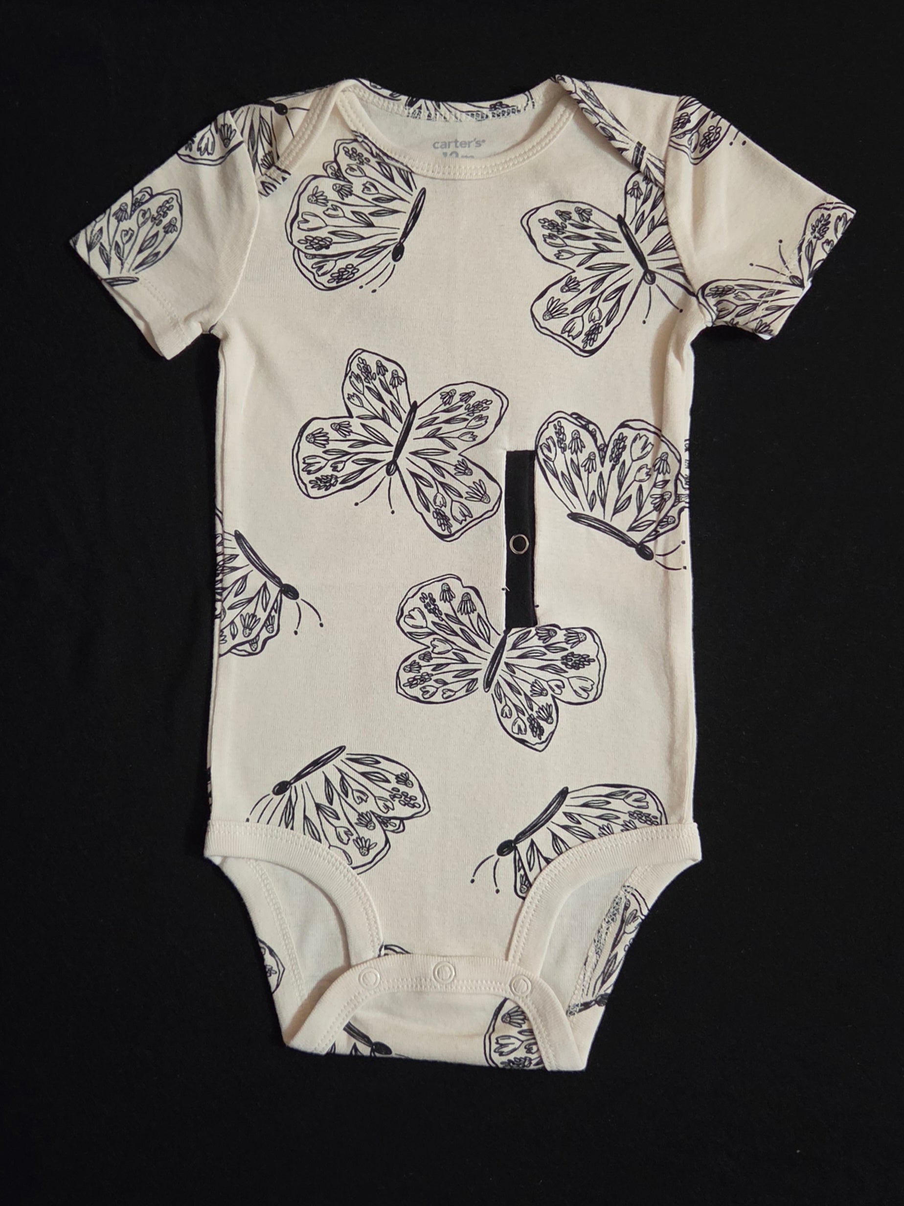 Gtube adapted bodysuit with black butterflies on a cream background.