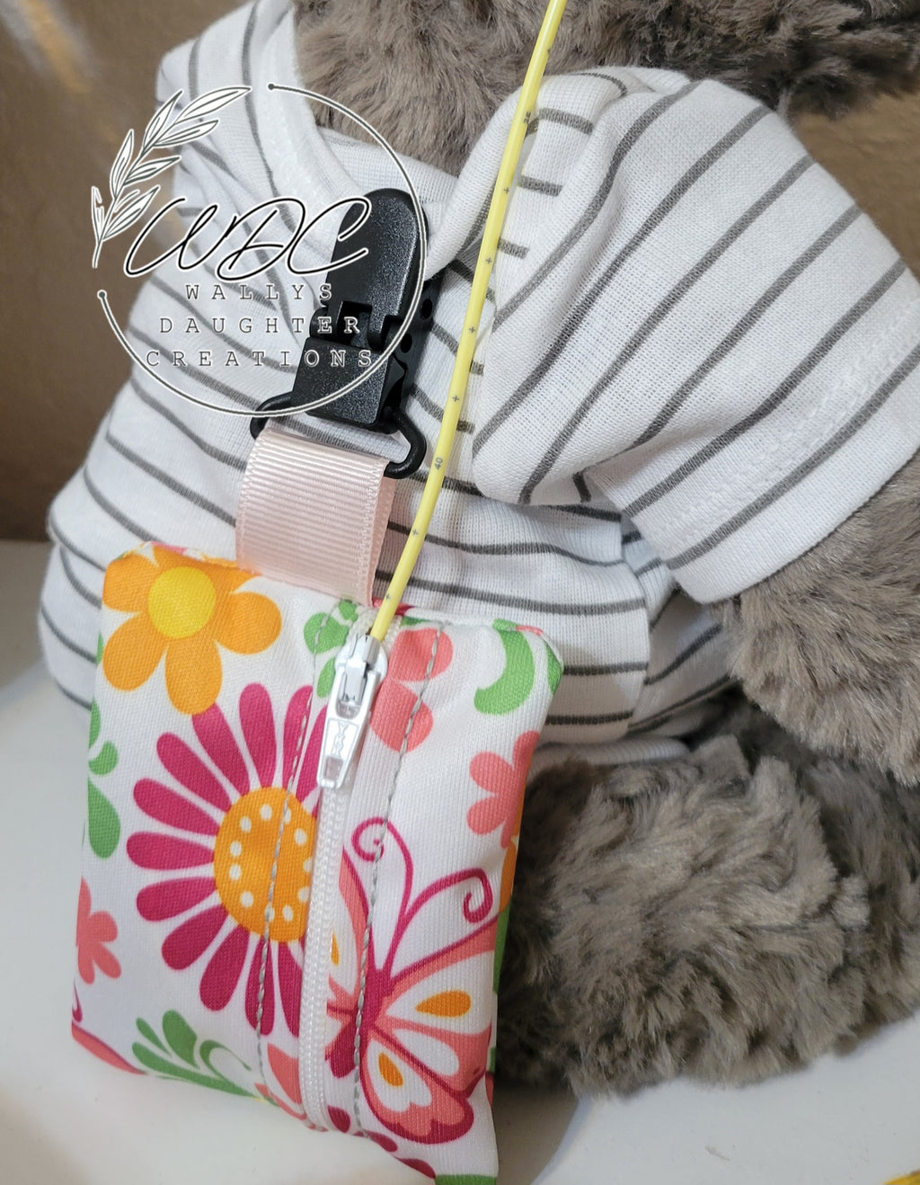 Back view of stuffie with ng tubing and a clip on zipper pouch