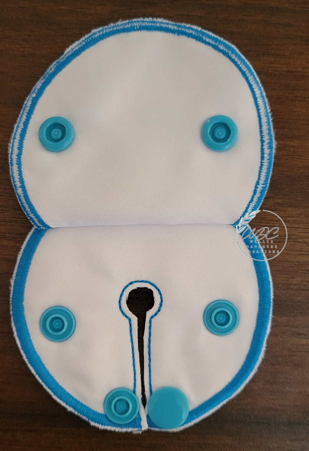 Inside view of a snap down covered pad with teal blue snaps and thread