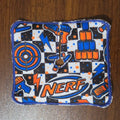 Trach pad with checkerboard background and Nerf items in orange and blue