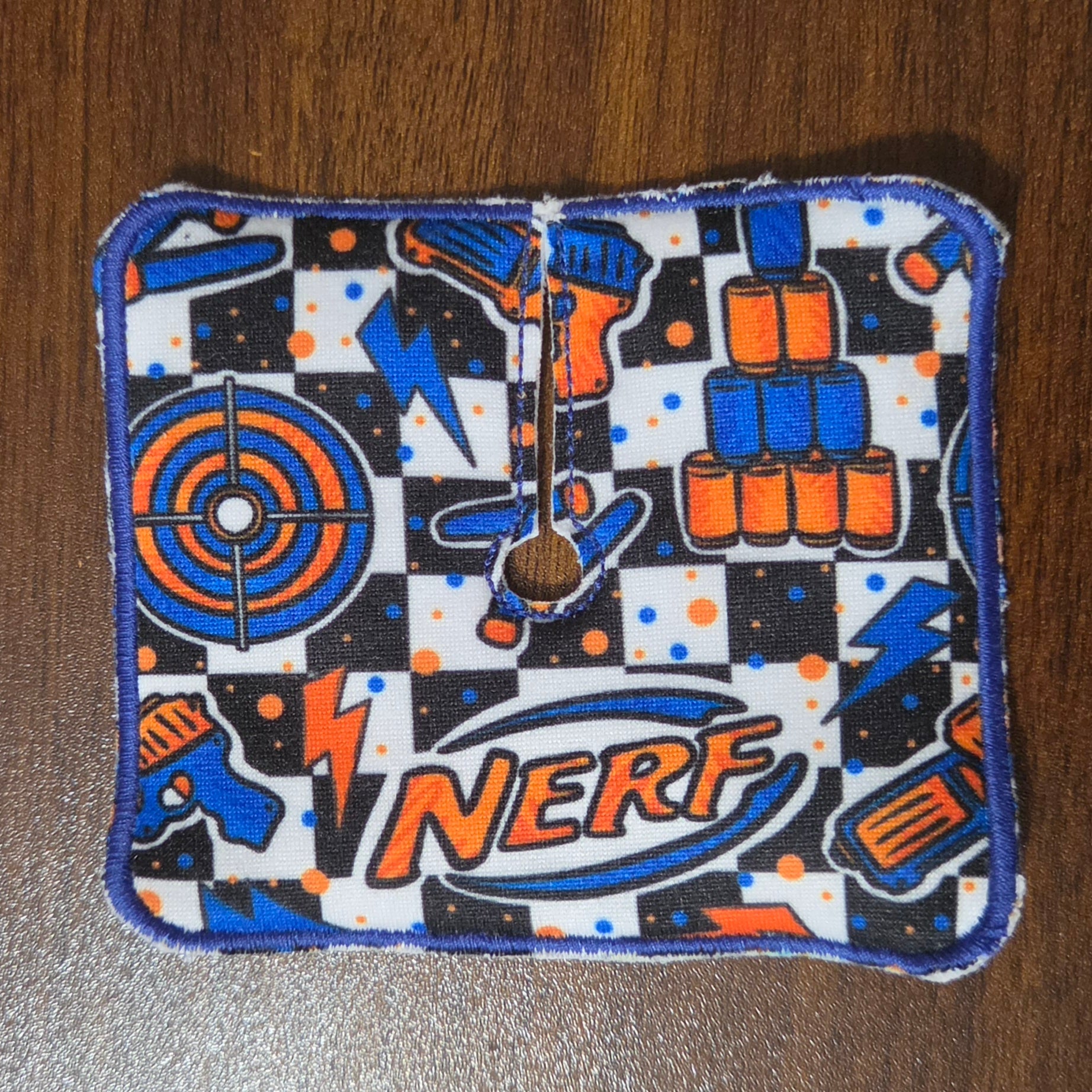Trach pad with checkerboard background and Nerf items in orange and blue