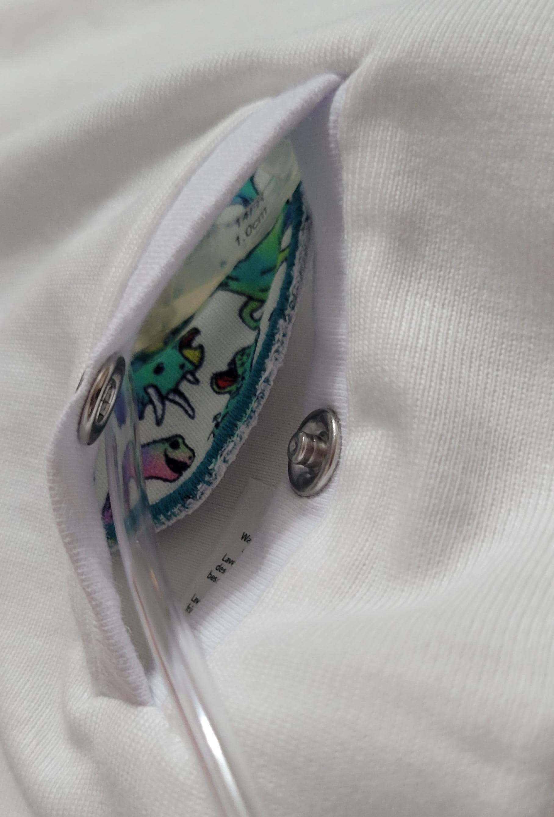 Close-up of a colorful button on a white shirt