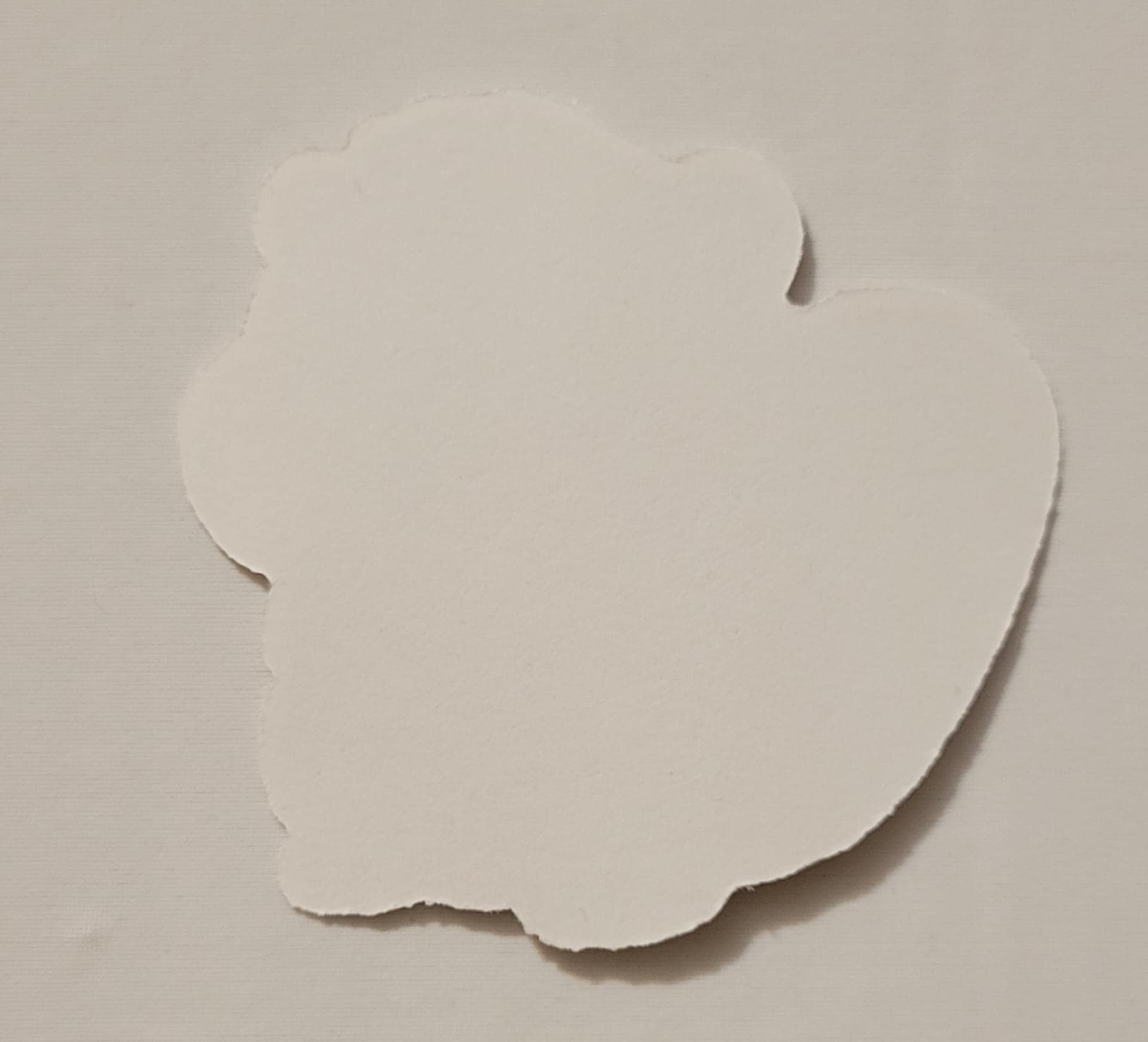 White paper cutout of a sticker shape on a beige background