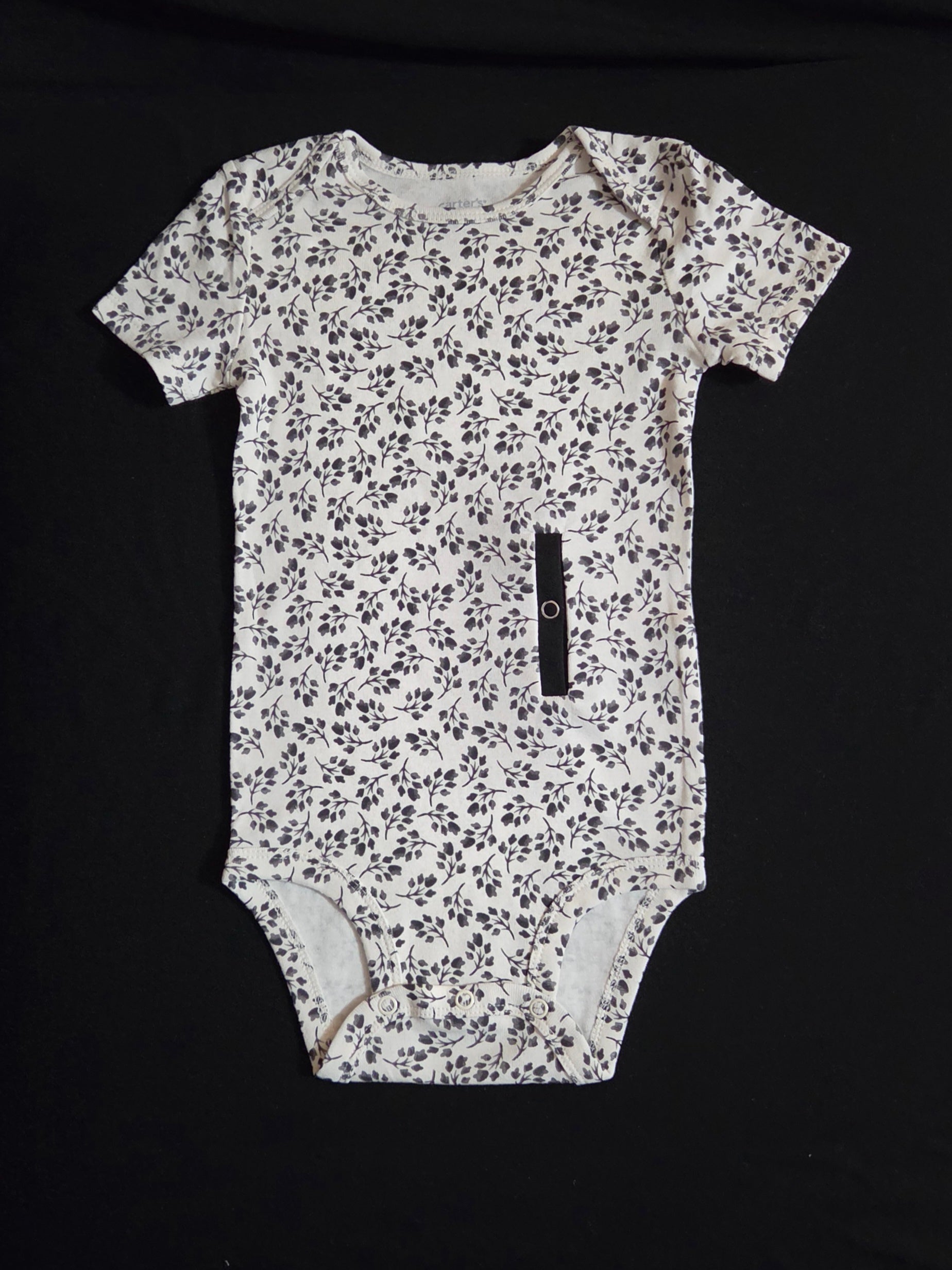 gtube adapted bodysuit with black leaves on a cream background 