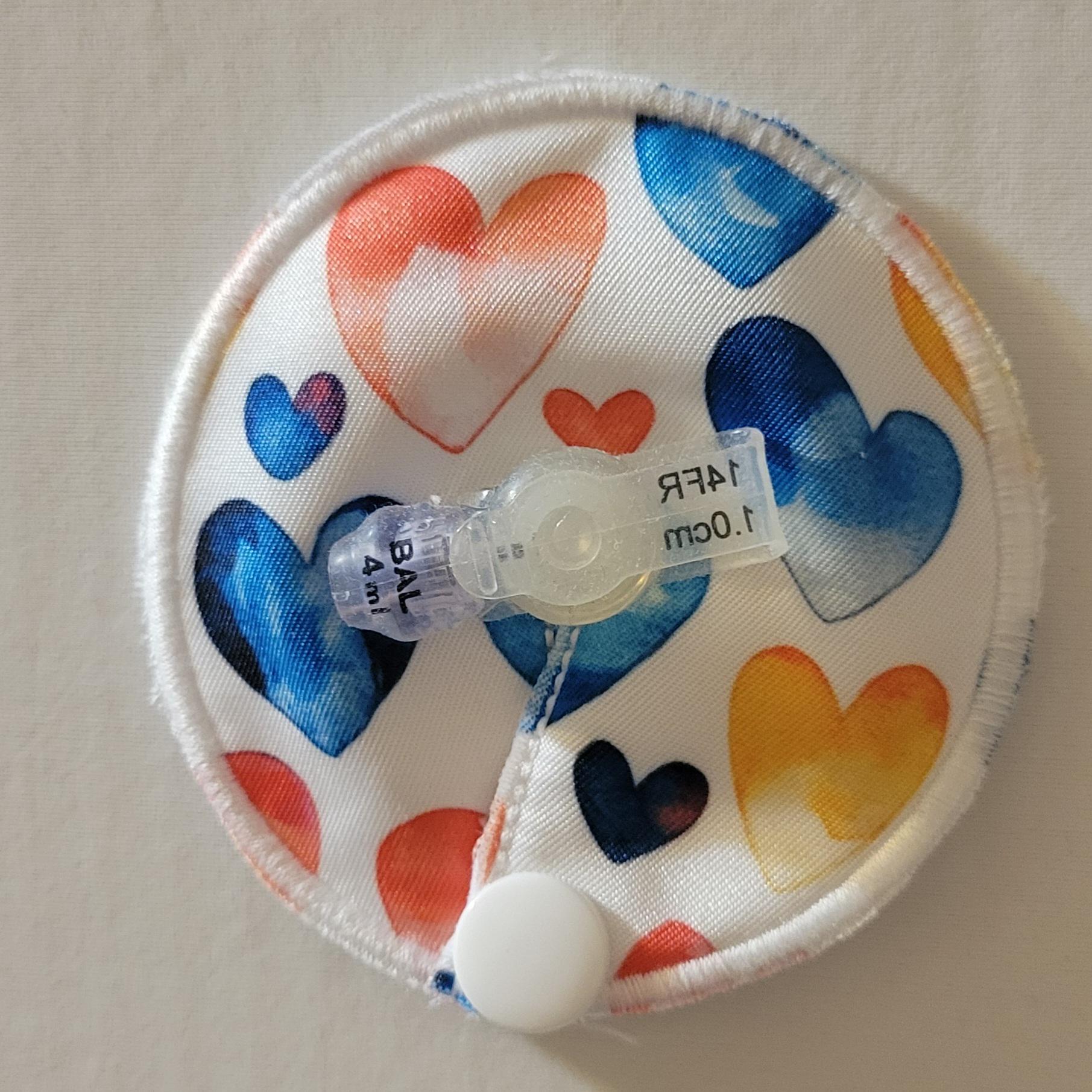 Round fabric pouch with colorful heart patterns and a clear valve on a beige background