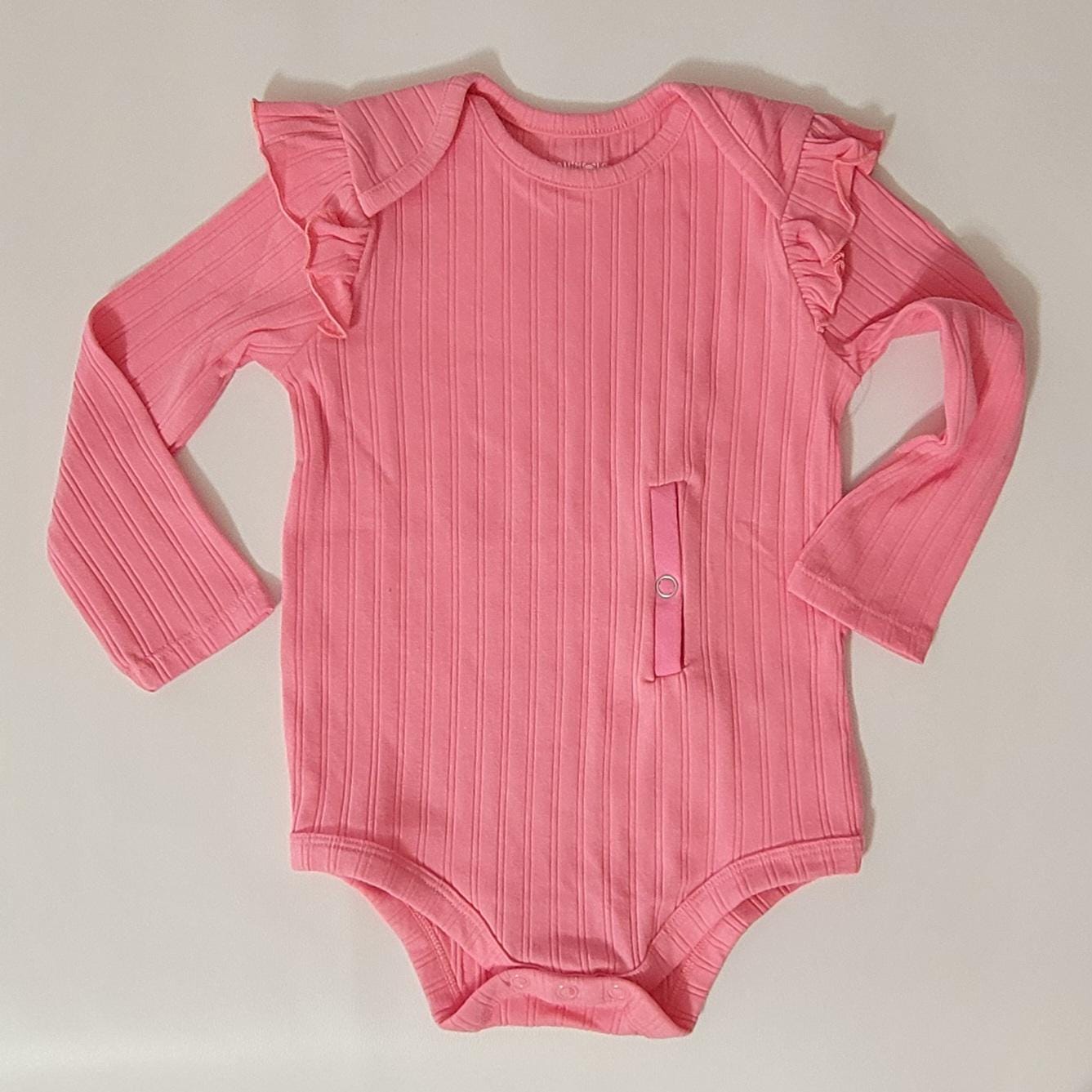 Pink baby bodysuit with ruffled long sleeves on a beige background