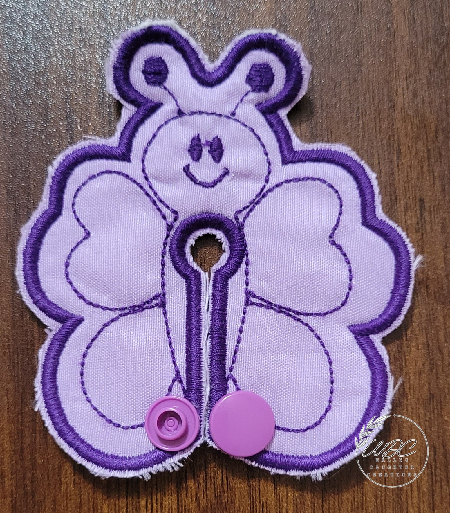 Butterfly shaped gtube pad on a light purple fabric with dark purple colored thread