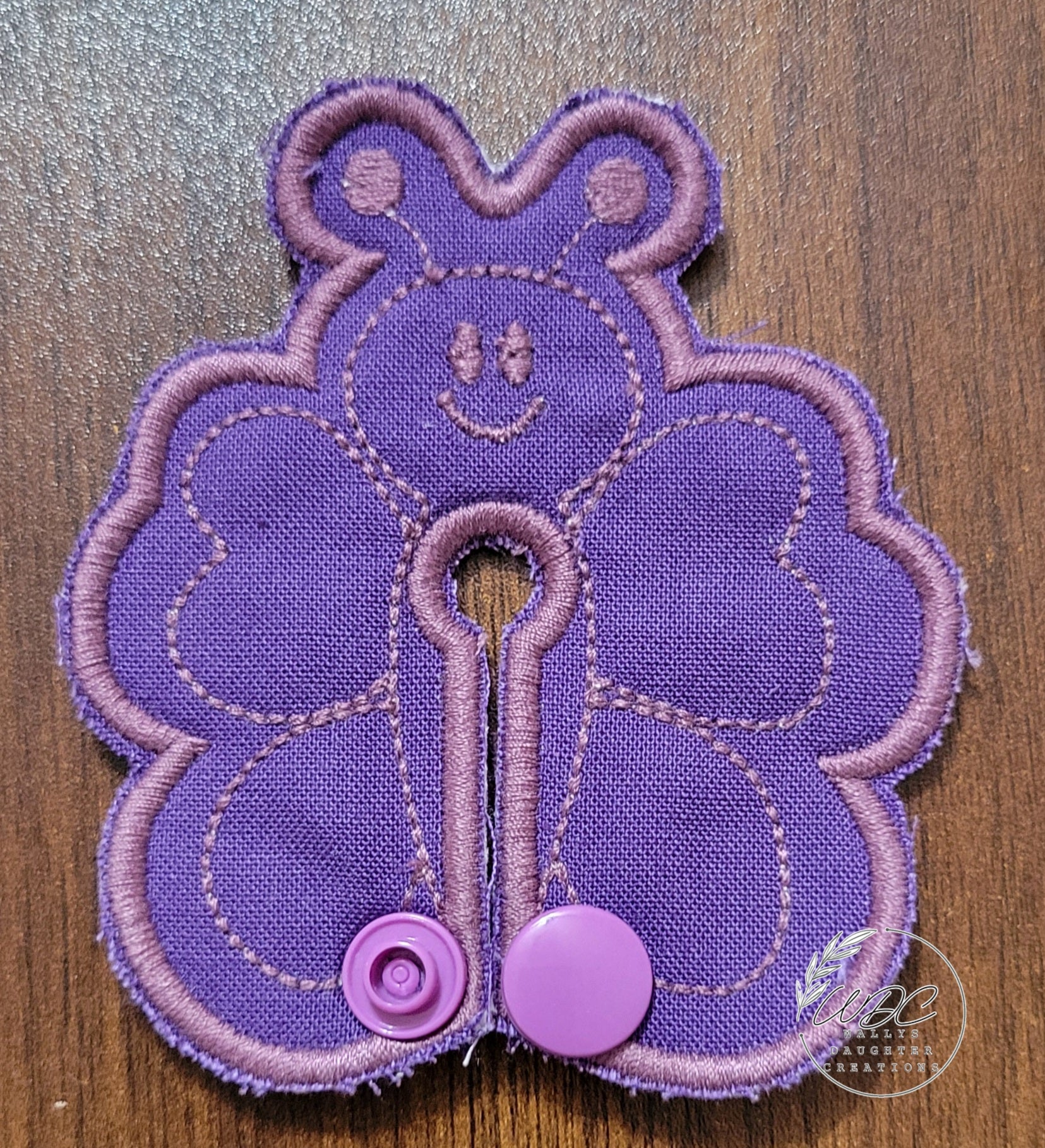 Butterfly shaped gtube pad on a dark purple fabric with light purple thread